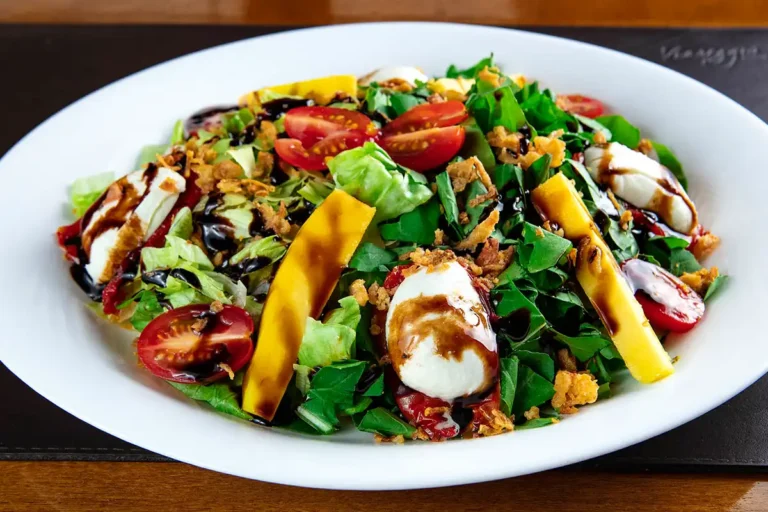 Insalata Tropicale - Alface americana, rúcula, tomate seco, tomate cereja, fatias de manga, muçarela de búfala, cebola crispy e molho balsâmico cremoso.